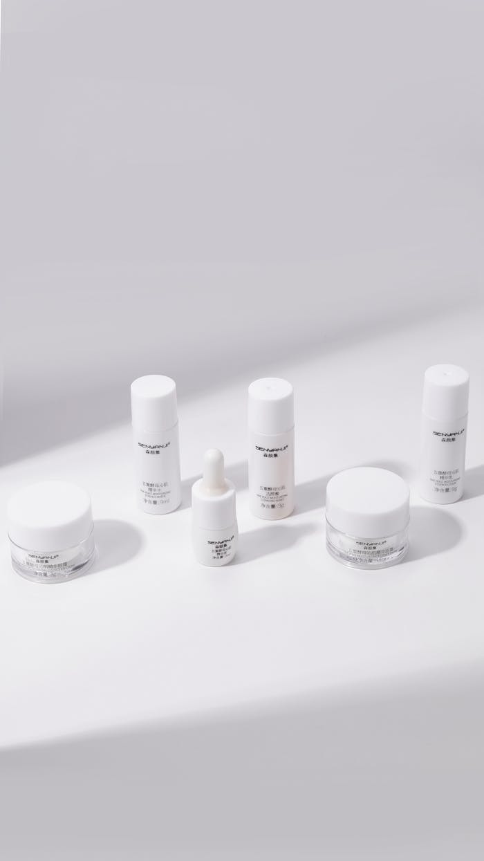 White cosmetic bottles and jars arranged in a minimalist style on a white backdrop.